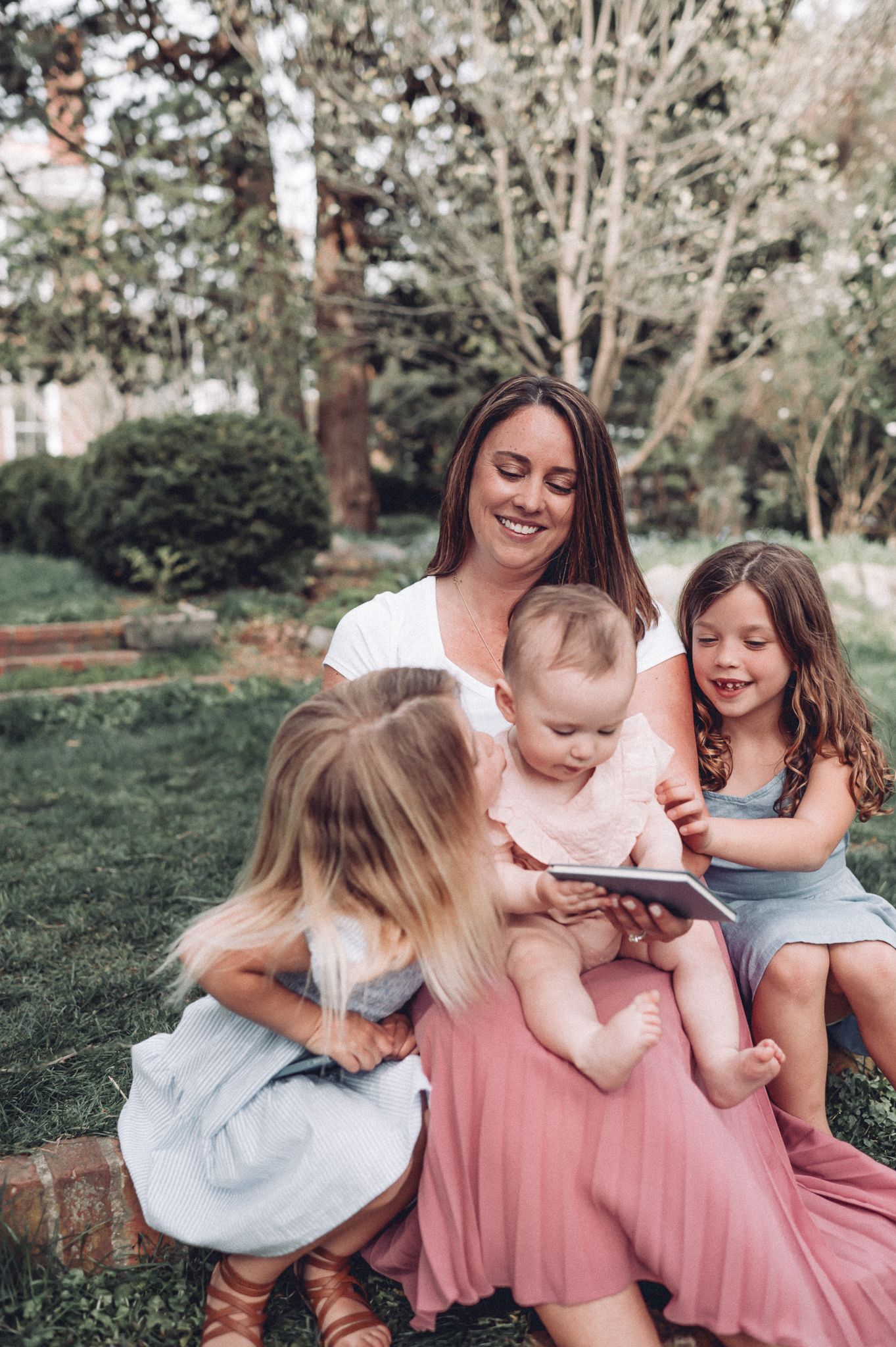 Candid family moment captured outdoors with everyone looking at a book together.