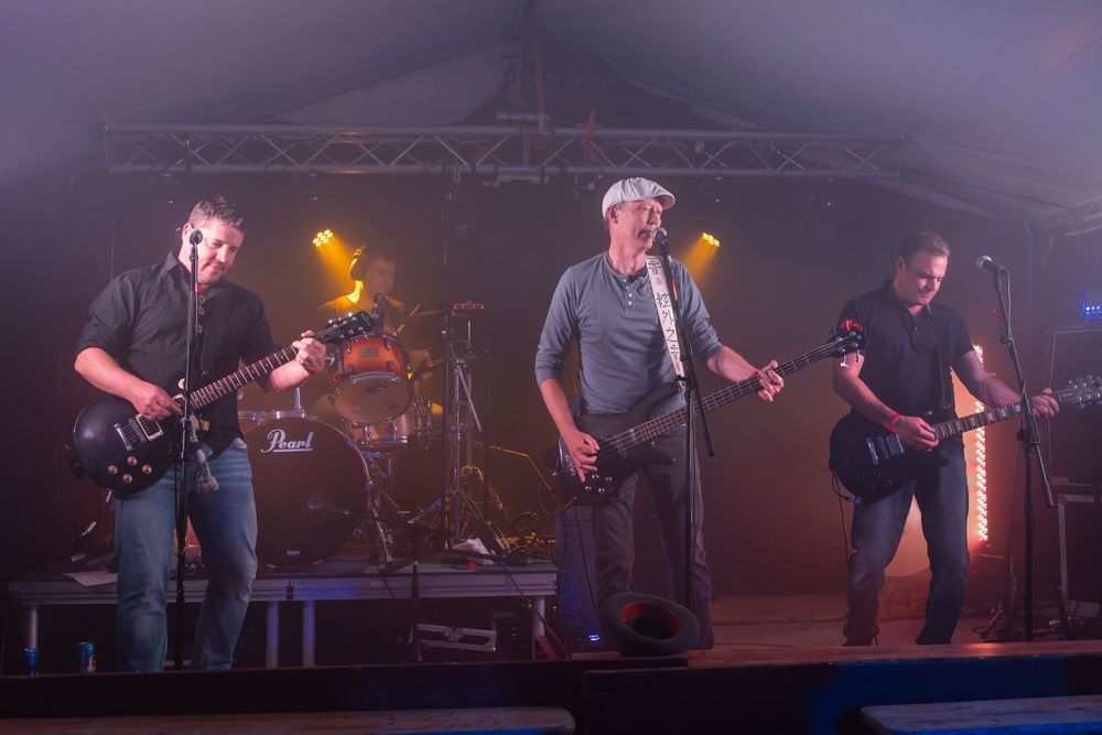 Band performs on stage through atmospheric fog with dramatic lighting effects.