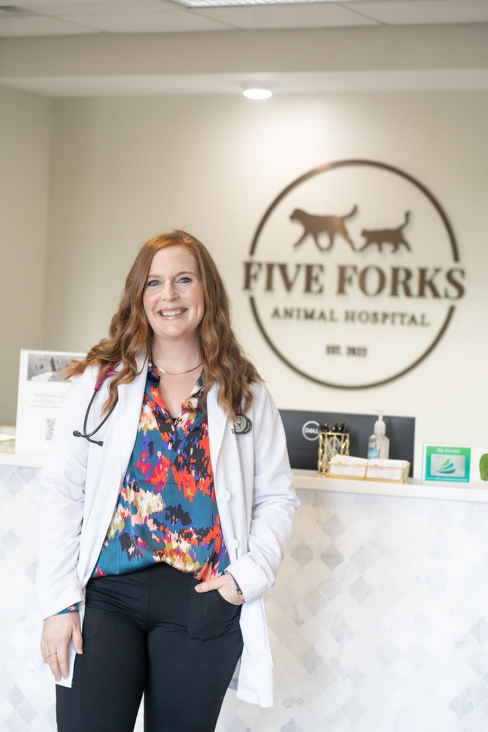 Veterinarian in white coat standing at Five Forks Animal Hospital reception.