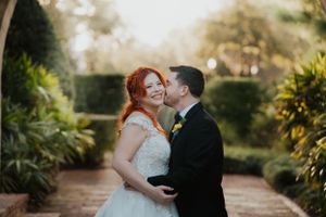 A romantic garden wedding moment with a couple embracing in elegant attire among lush greenery.