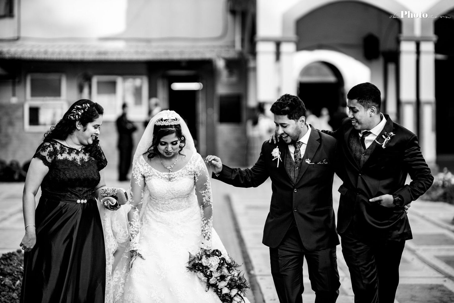 Wedding party walking together and laughing in black and white photograph.
