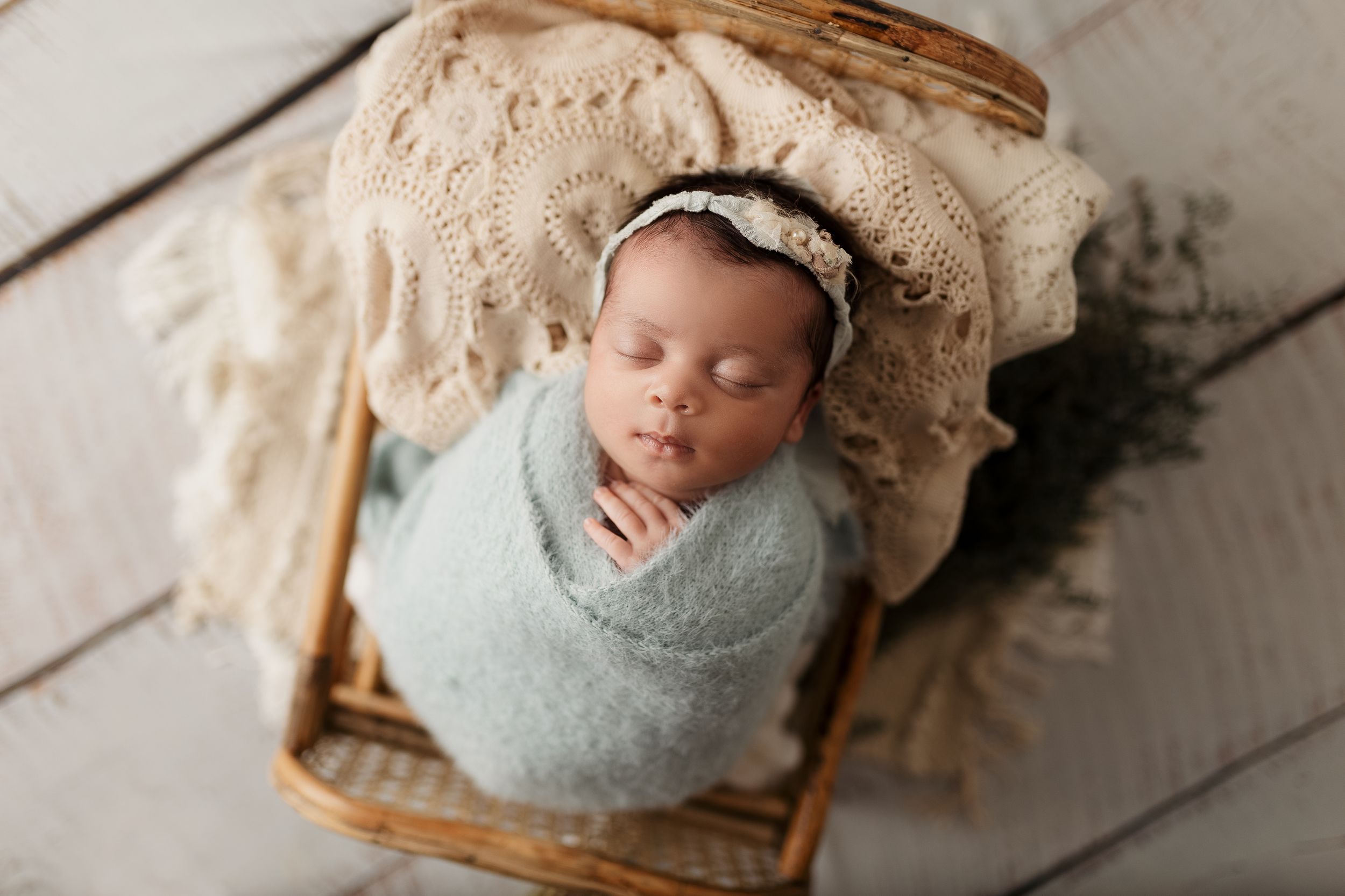 Rustic newborn photography with soft blue wraps and natural basket props.