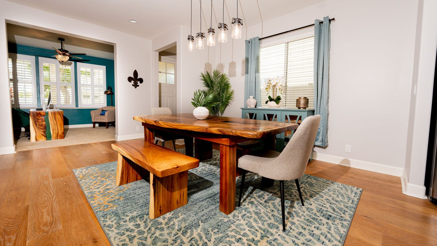 Modern open concept dining area with light wood floors, blue area rug, and pendant lighting fixtures.