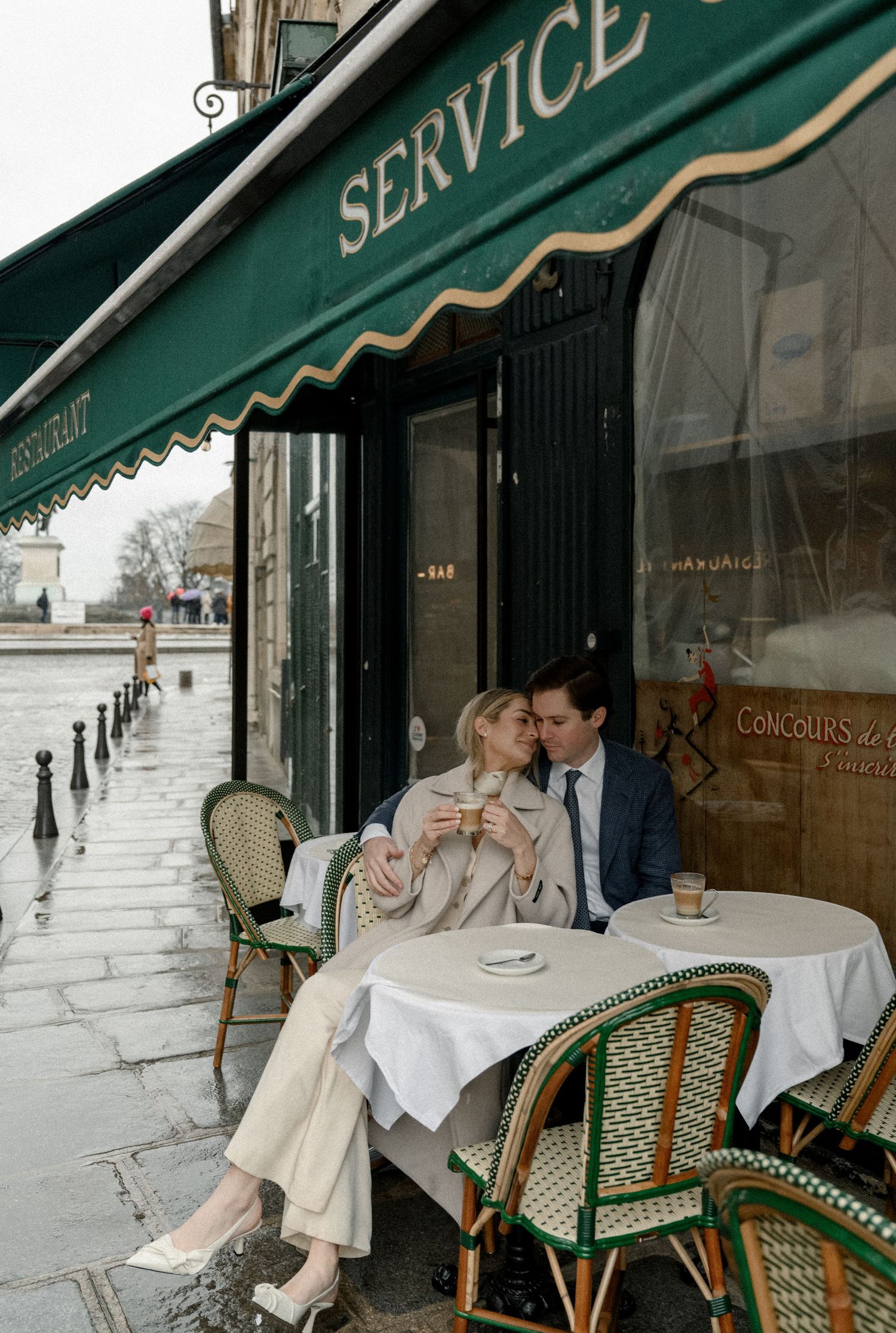 Romantic cafe scene outside a Parisian bistro with green awning on a rainy day.