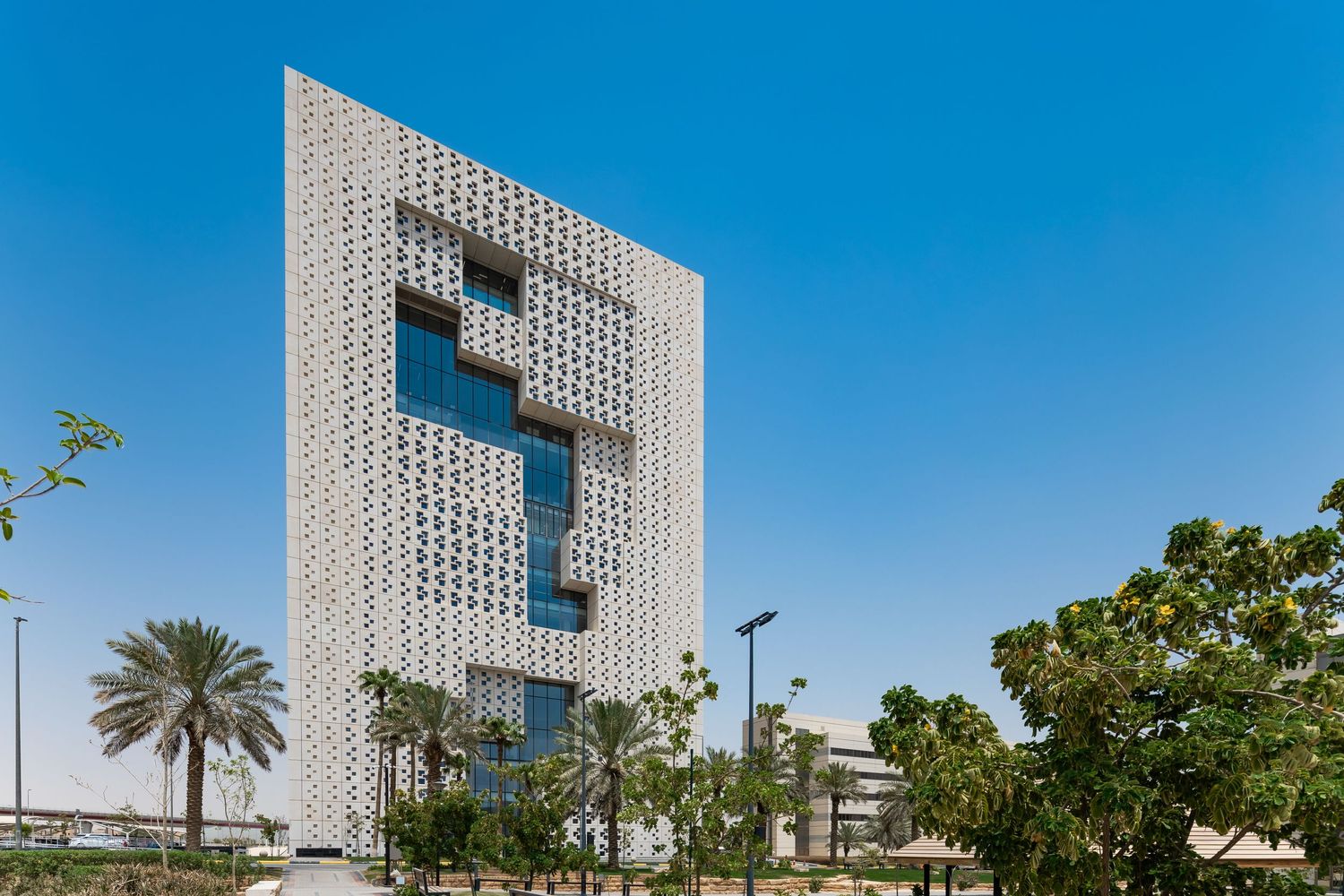 Distinctive white office building with abstract geometric cutout design surrounded by palm trees.