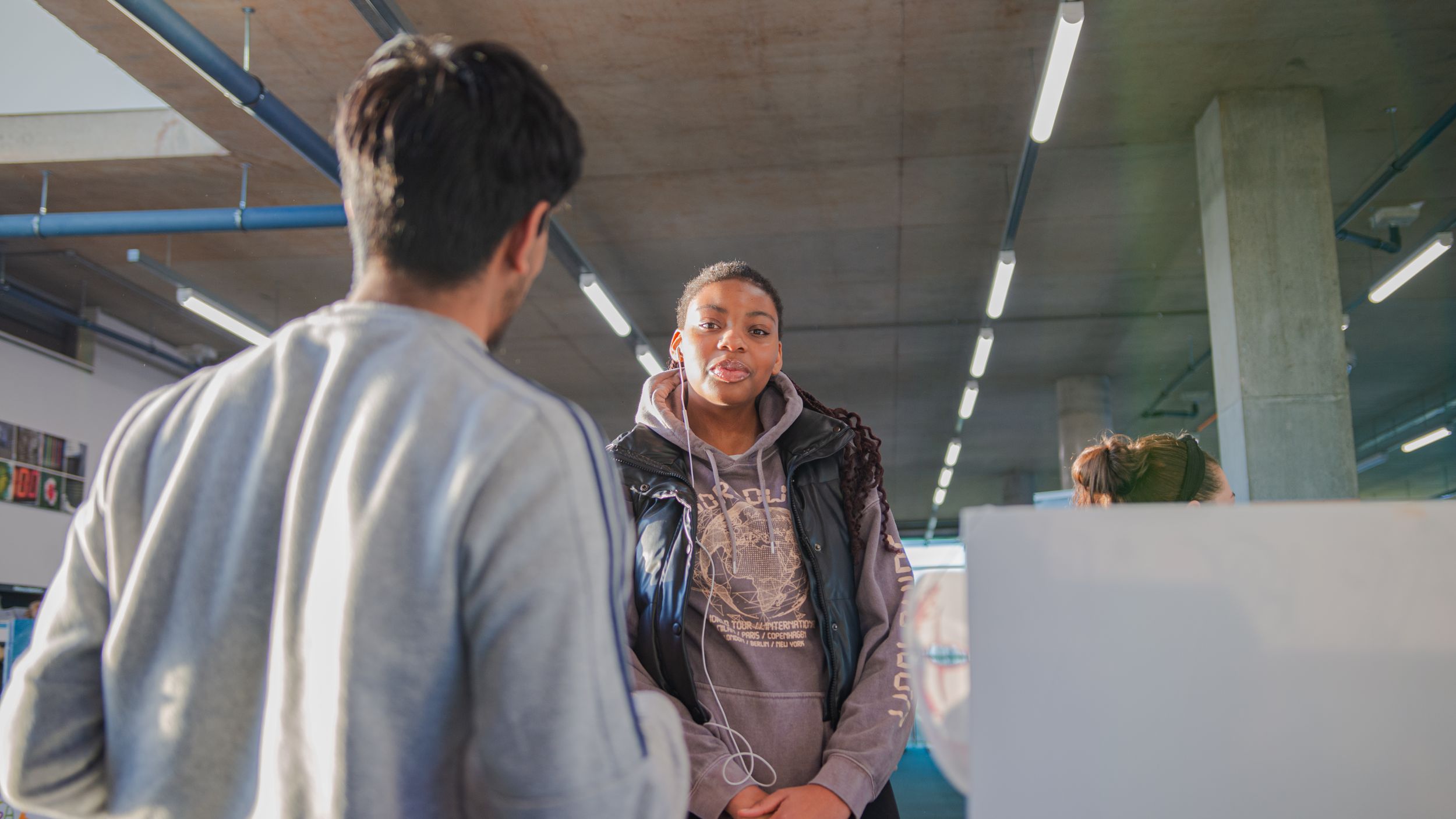 Two students converse at a reception desk in a modern educational building.