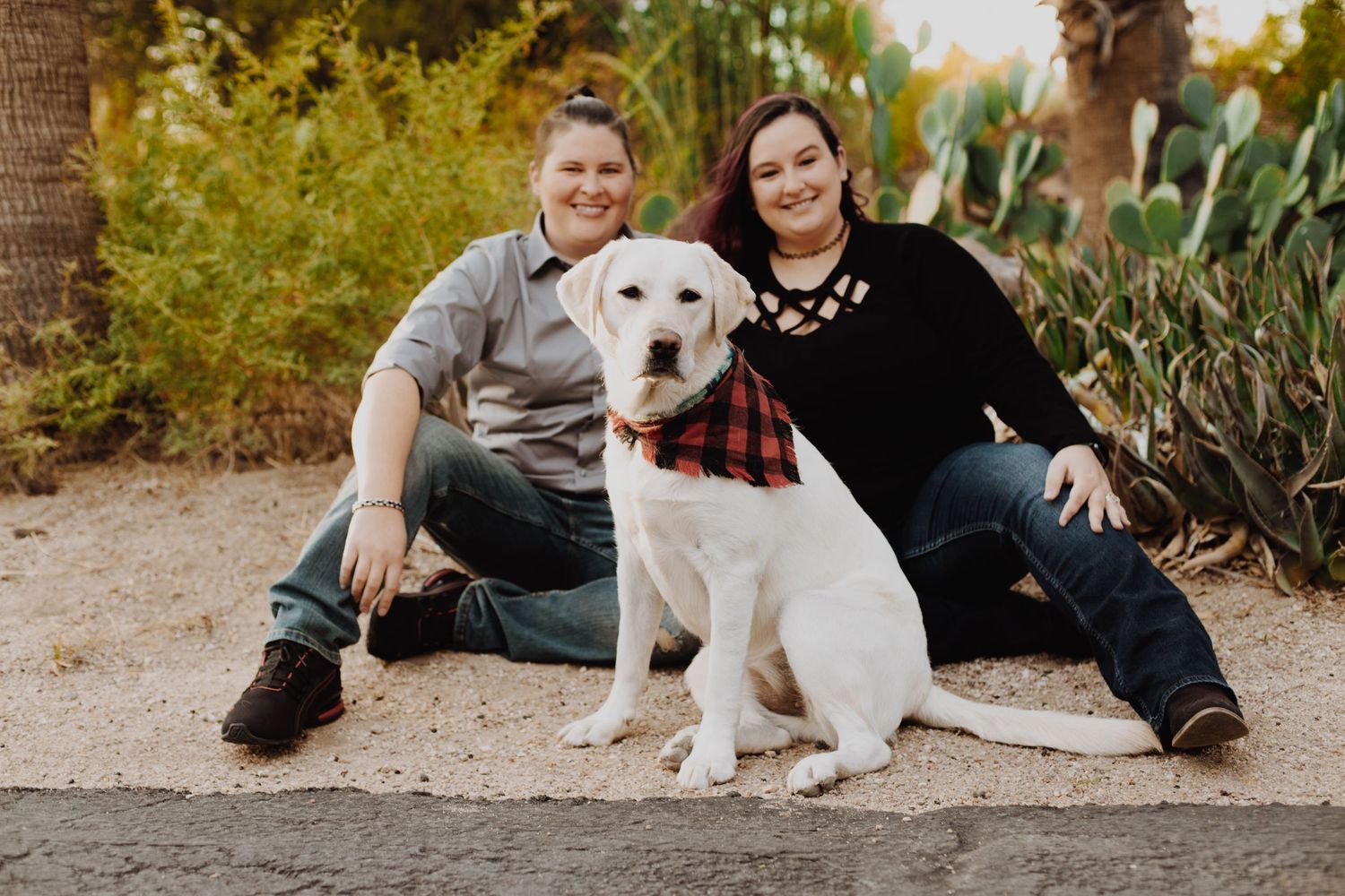 Pet dog joining outdoor portrait session with companions sitting on gravel path at sunset.