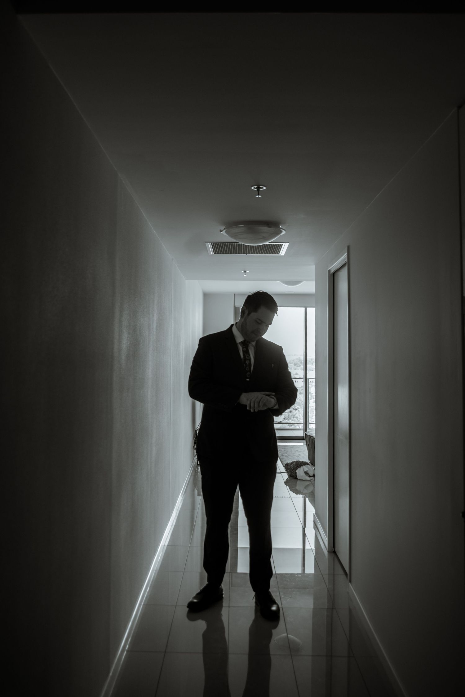Moody black and white portrait in a minimalist hallway.
