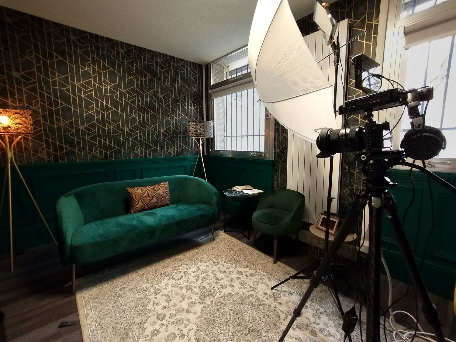 Modern photography studio setup with emerald green velvet couch and professional lighting equipment.
