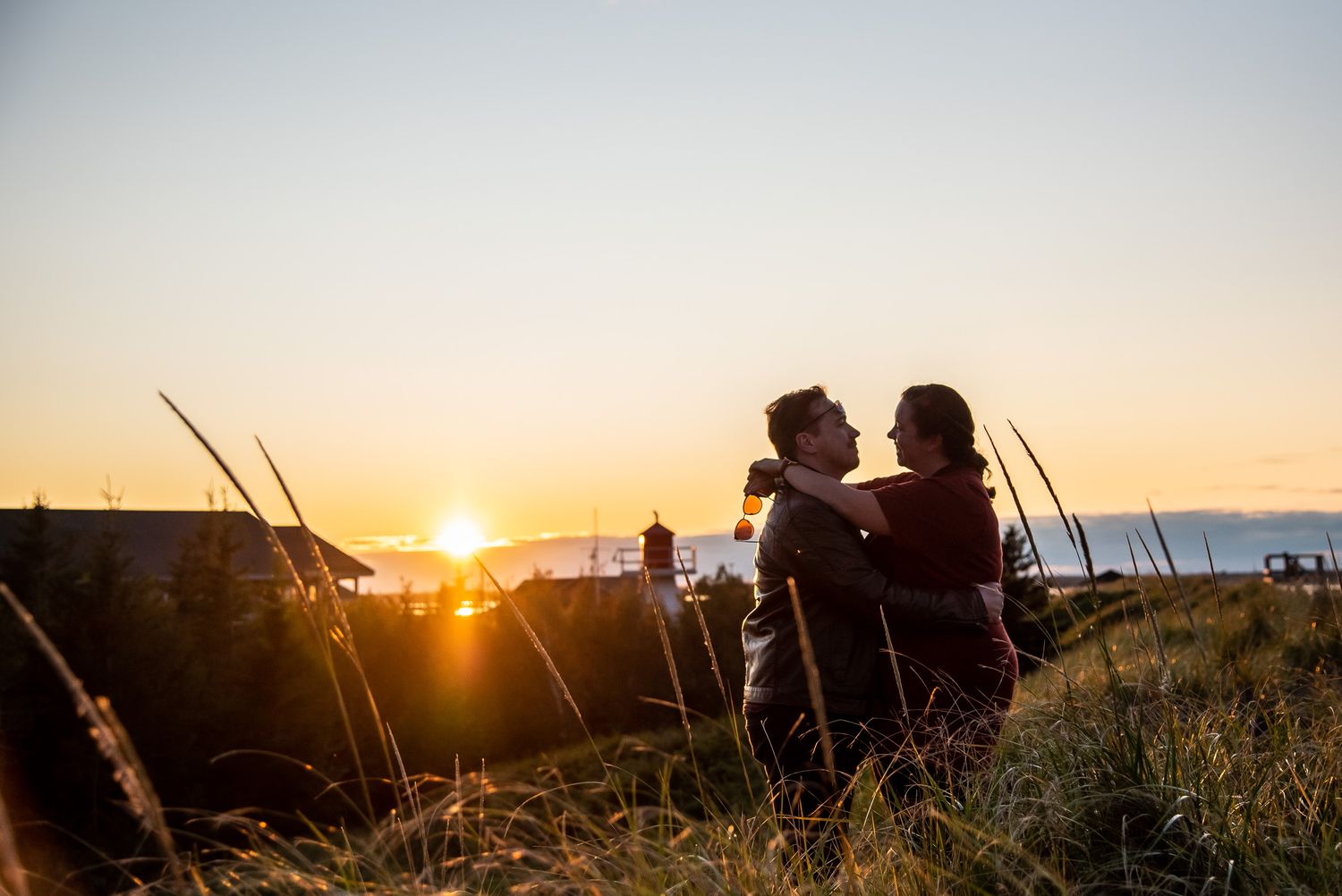 Couple sitting together watching golden sunset over scenic hilltop landscape.