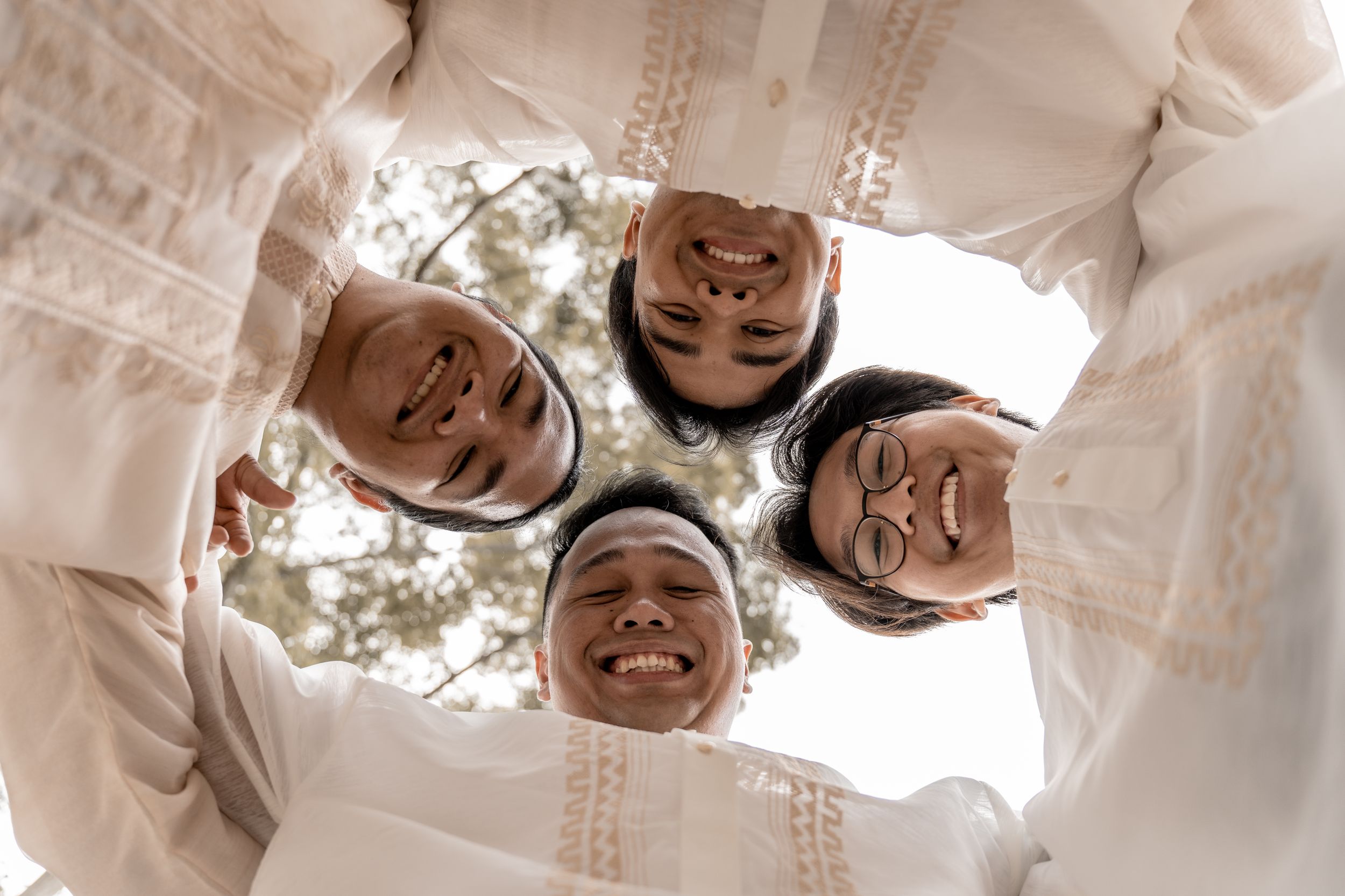 A fun photo taken from below showing a group in white traditional attire looking down at the camera.