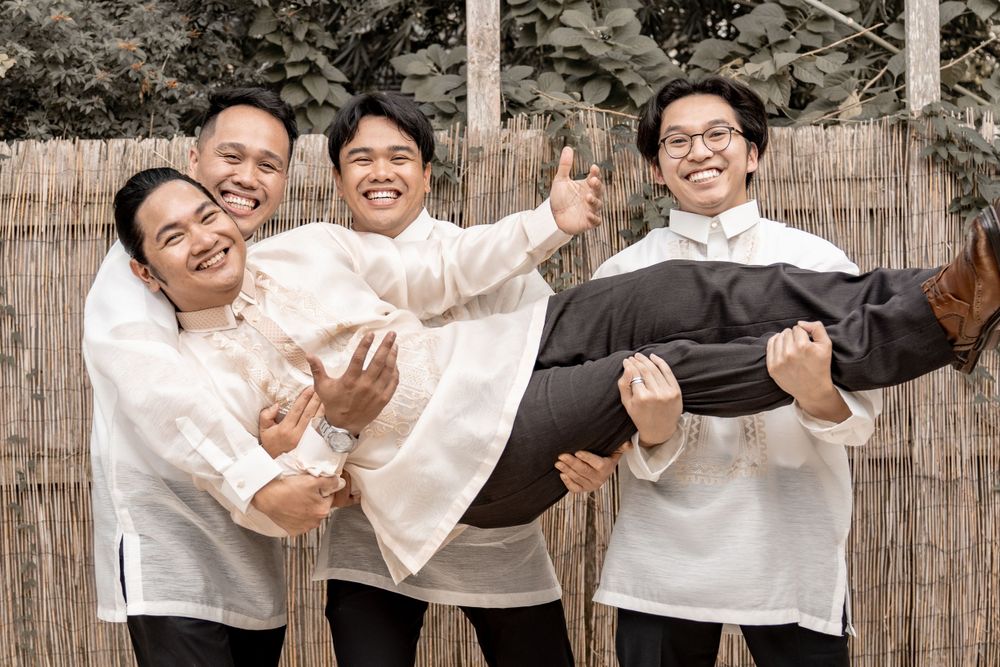 A joyful group in matching white outfits playfully carrying a member of the group.