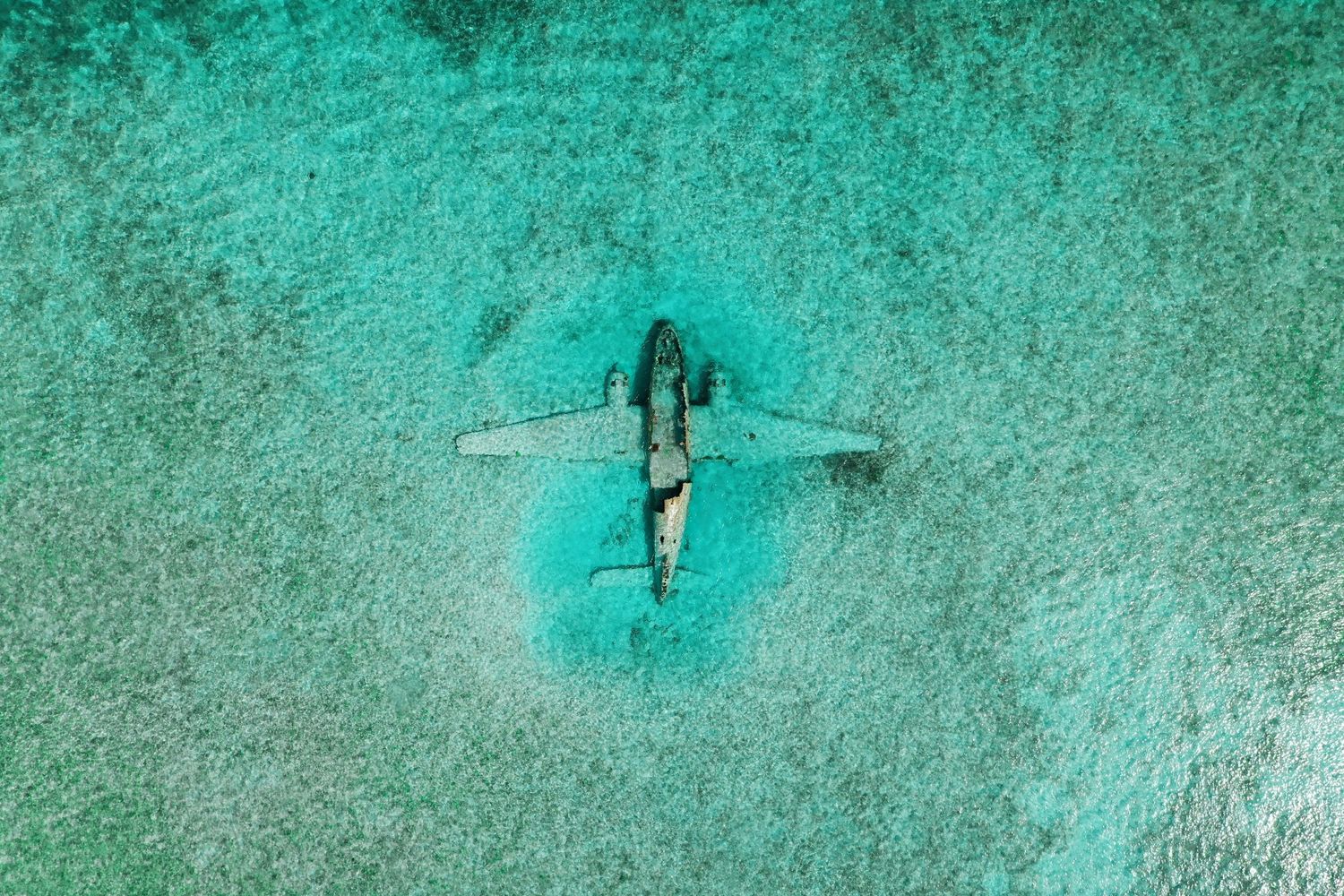 Drone photo of Norman’s Cay plane wreck in clear turquoise Bahamian waters.