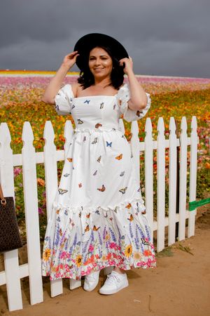 A playful pose by a white picket fence surrounded by colorful wildflowers.