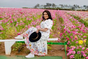 A person in a white dress dances through a field of pink cosmos flowers.