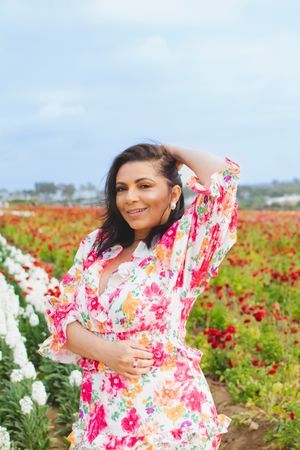 A person in a floral dress poses in a colorful flower field.