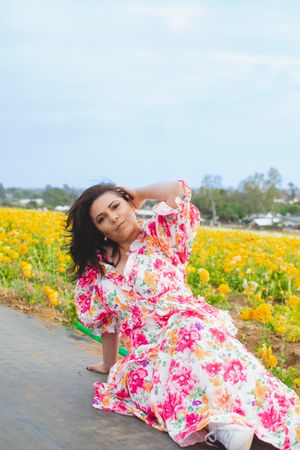 A dreamy pose in a floral dress among yellow wildflowers.