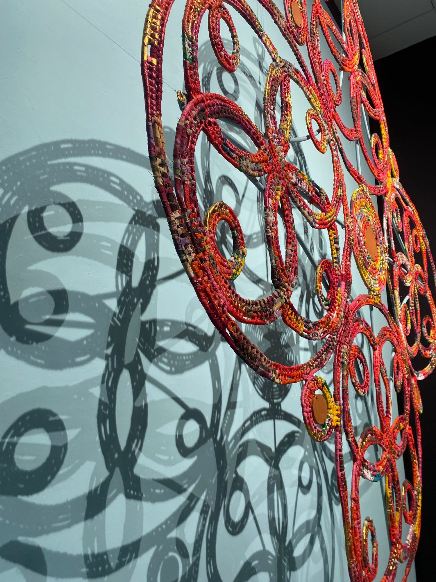Ornate red metal circular design casting dramatic shadows on wall.