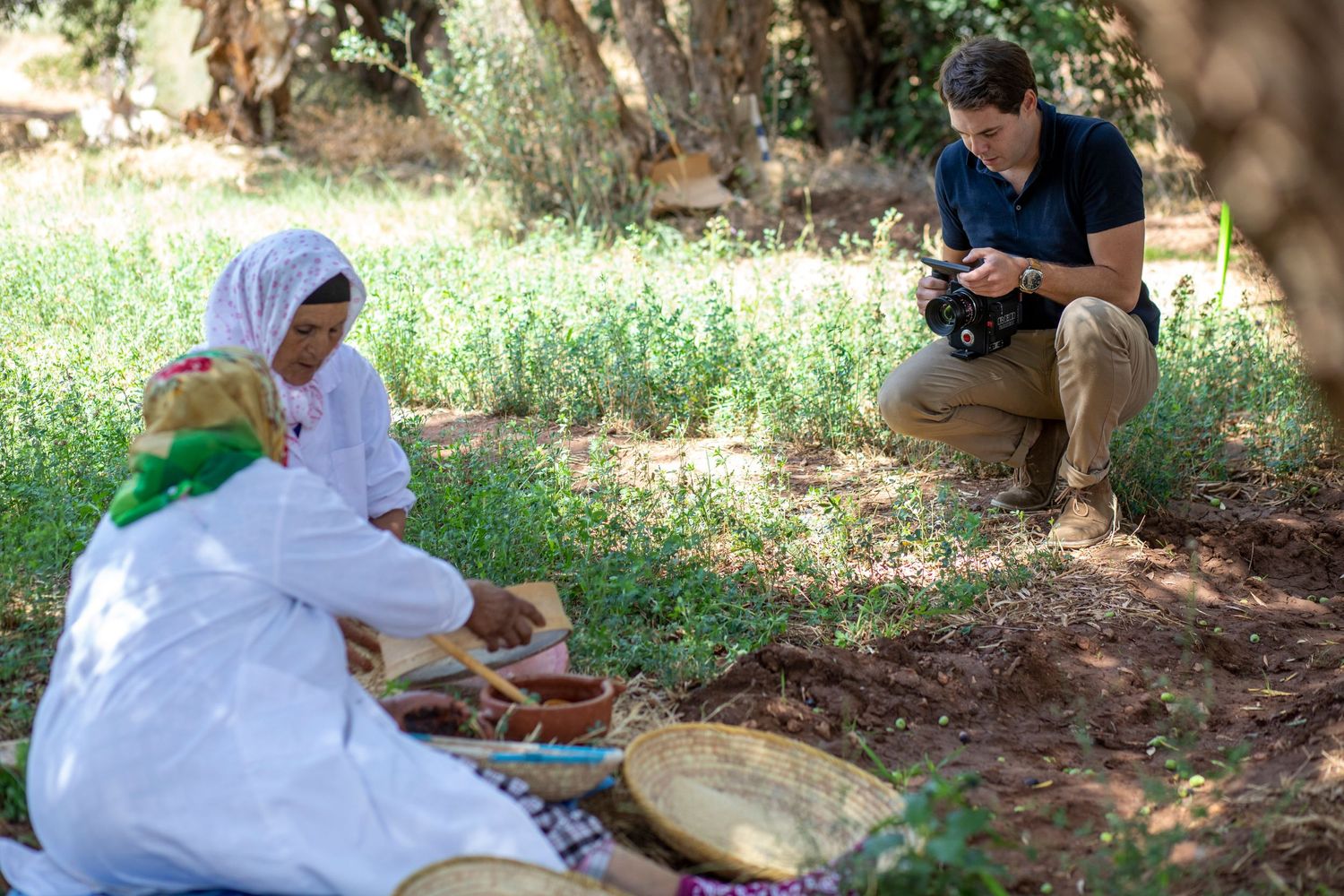 Traditional cooking demonstration outdoors under dappled sunlight.