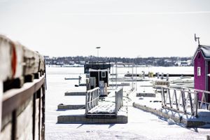 Row of fishing shacks and piers extending into snowy harbor landscape.