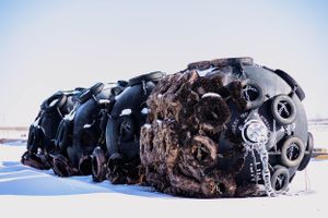 Row of weathered naval mines displayed in snowy outdoor setting.