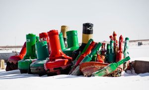 Colorful collection of nautical buoys arranged in snow during winter.