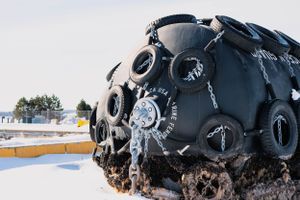 Large black naval mine covered in ice displayed as outdoor monument.