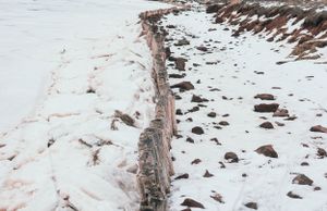 Rocky winter shoreline covered in snow extends along frozen waterfront.