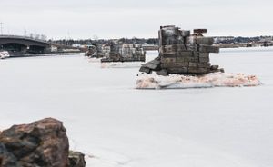 Stone pillars emerge from frozen water beneath a bridge in winter conditions.