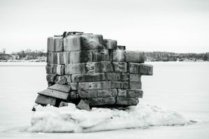 Stone breakwater covered in snow extends across frozen winter waters.