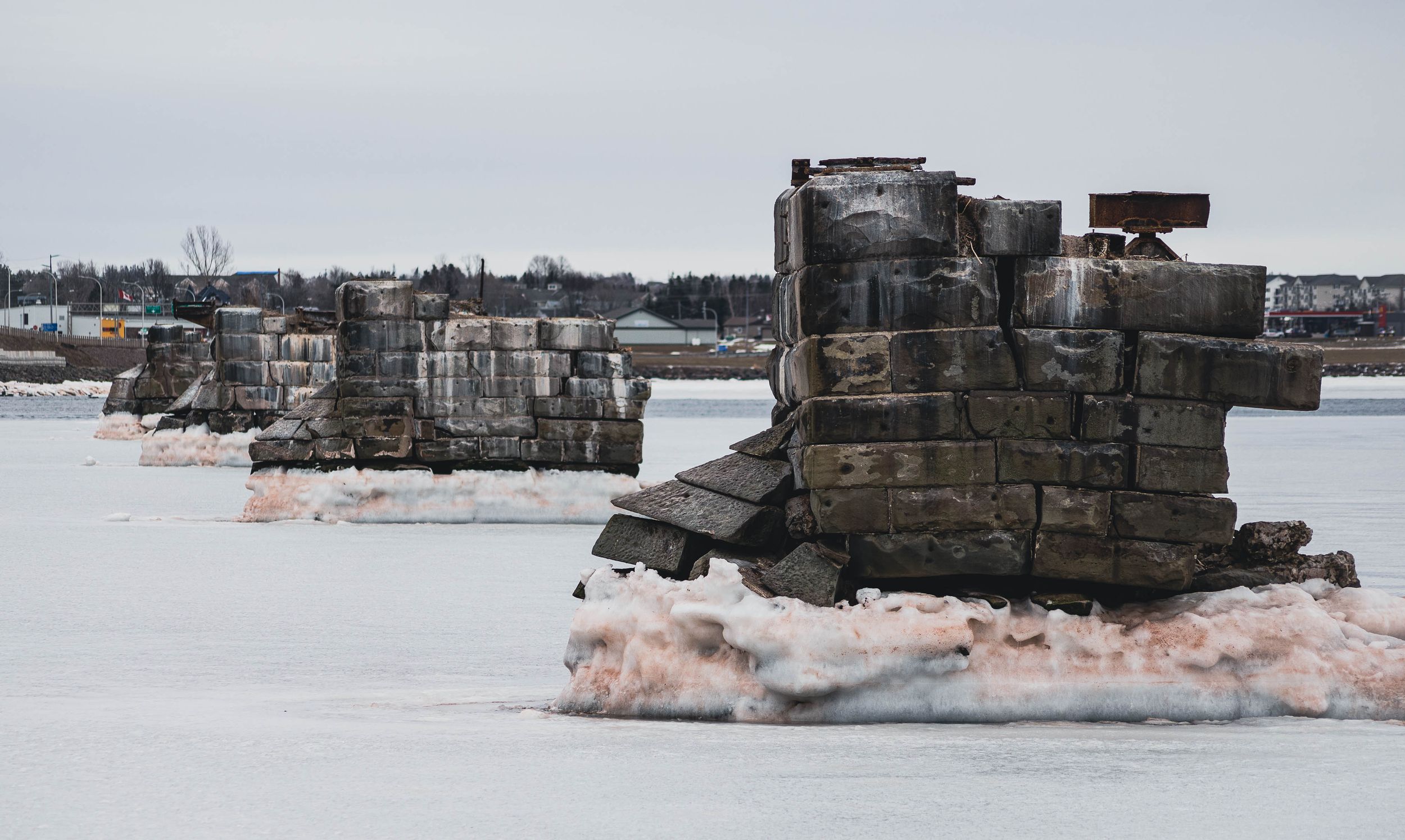 Snow-covered stone breakwater stretches across frozen winter landscape.