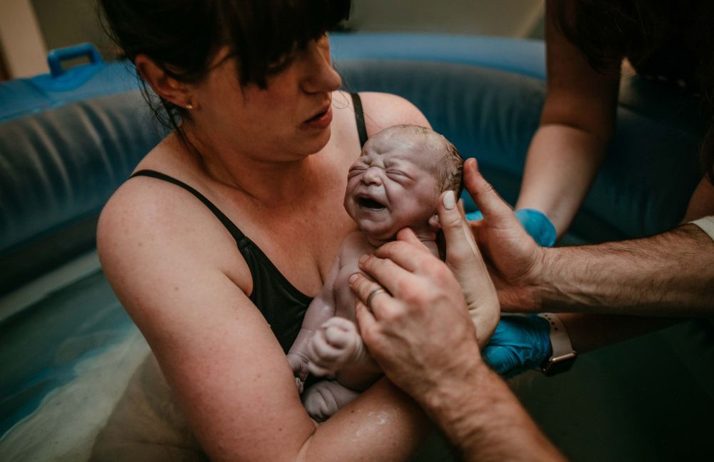 mother holds newborn in water birth portland oregon birth photographer