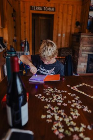 Wooden table with scattered puzzle pieces in a warmly lit room.