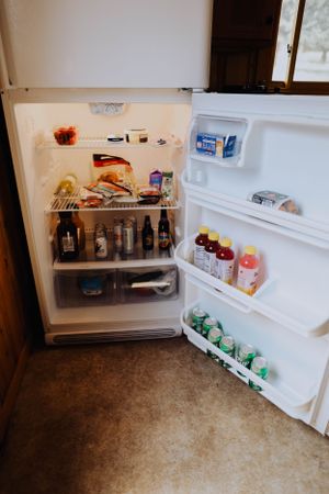 Open white refrigerator stocked with various food items and beverages.