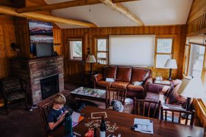 Rustic cabin interior with exposed wooden beams and comfortable seating areas.
