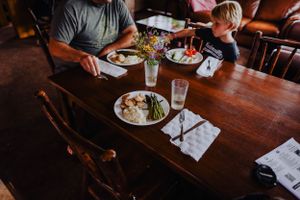 People gathered around a wooden dining table in a cozy restaurant setting.