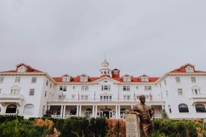 Exterior view of a grand historic hotel with white facade and red tile roof against cloudy sky.