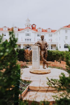 Bronze statue memorial with white colonial style building in the background.
