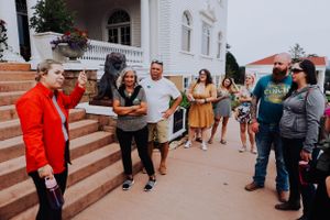 Group of visitors walking up concrete steps outside a white building.