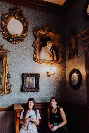 Ornate Victorian room interior with gilded mirrors and patterned wallpaper.