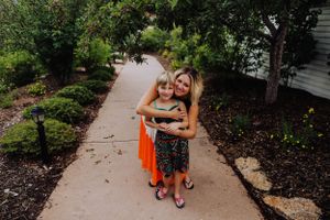 Two people share a joyful moment while hugging on a concrete path lined with garden beds.