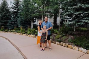 A small group stands together on a curved pathway surrounded by evergreen trees and aspen.