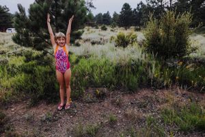 A person in a pink swimsuit strikes an energetic pose against a natural desert landscape.
