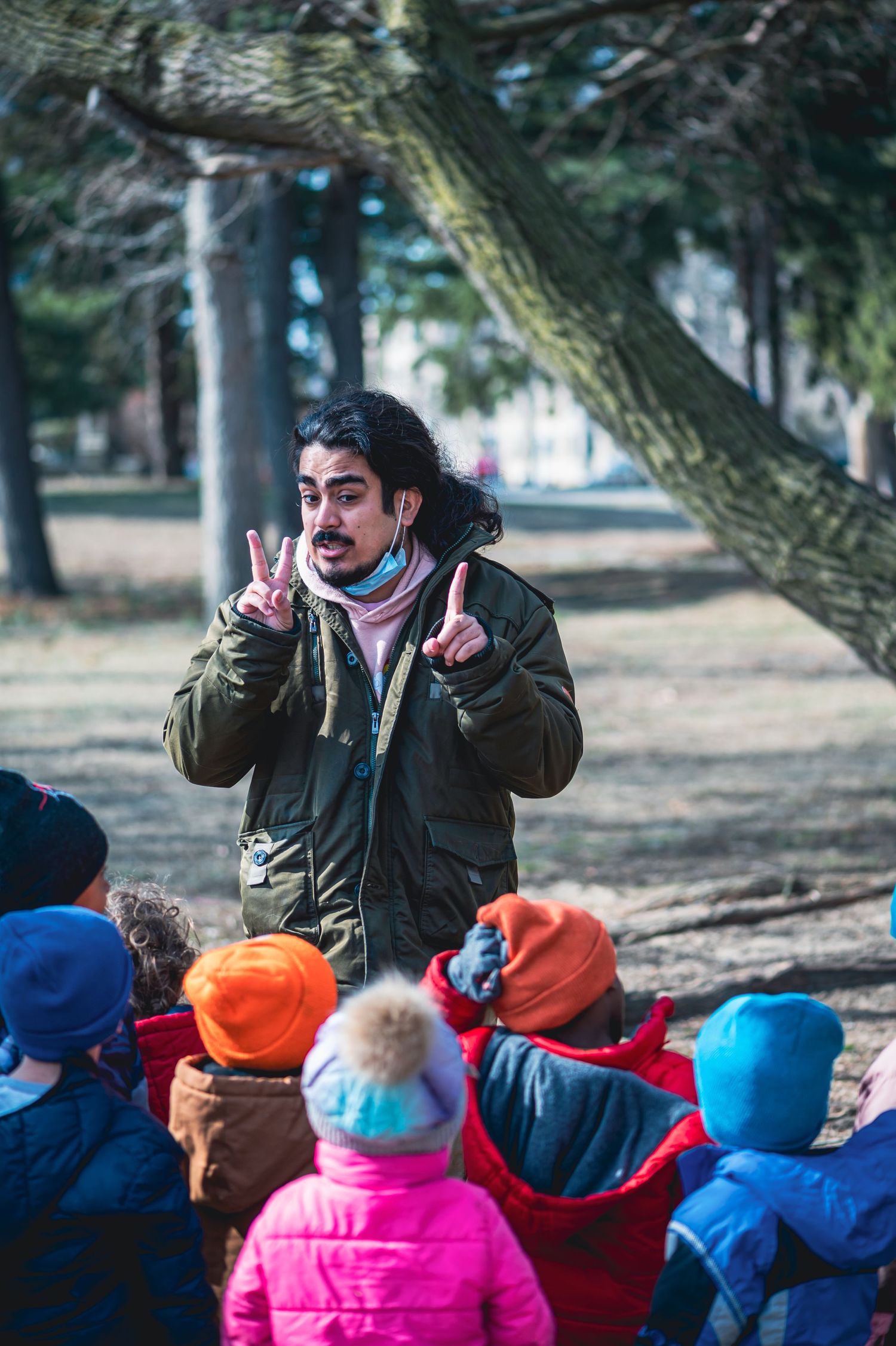 Outdoor educator engaging with children wearing colorful winter hats.
