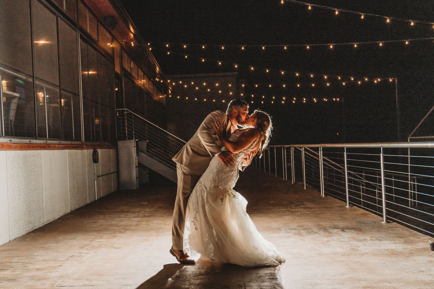String lights illuminate an industrial venue space creating a romantic wedding atmosphere.