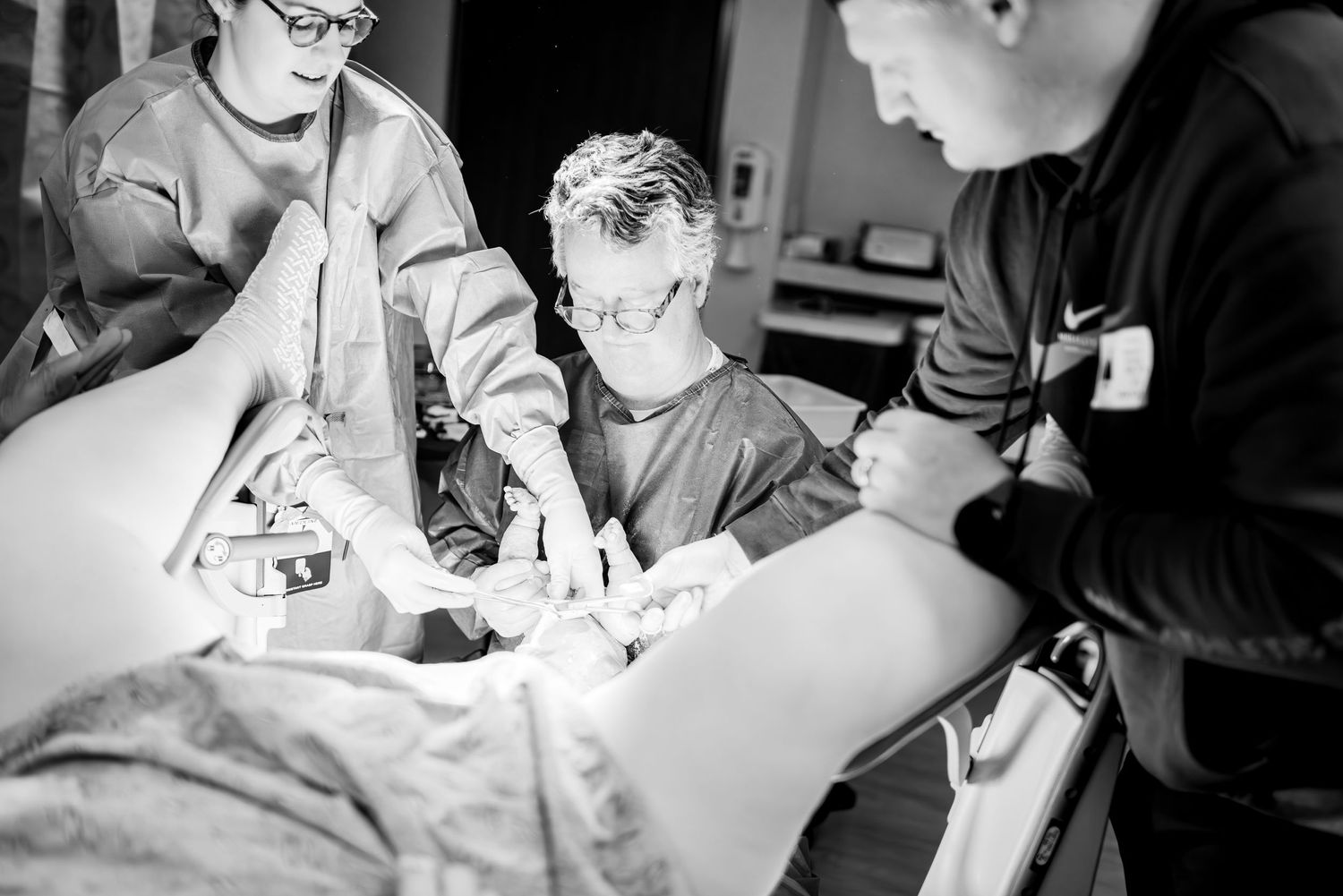 Hospital staff attend to a patient during a medical procedure in black and white.