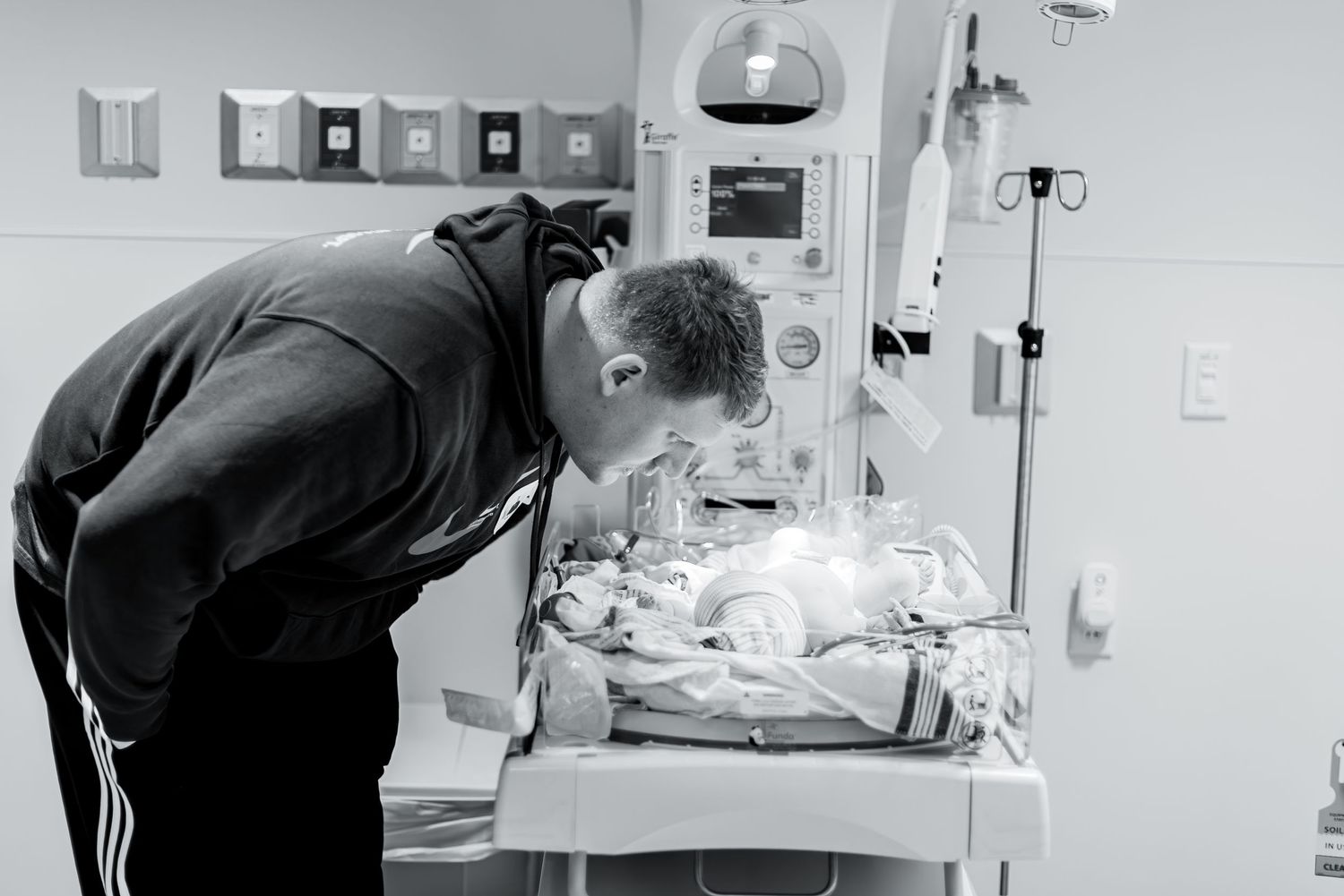 Person looking over a hospital bassinet containing medical equipment.