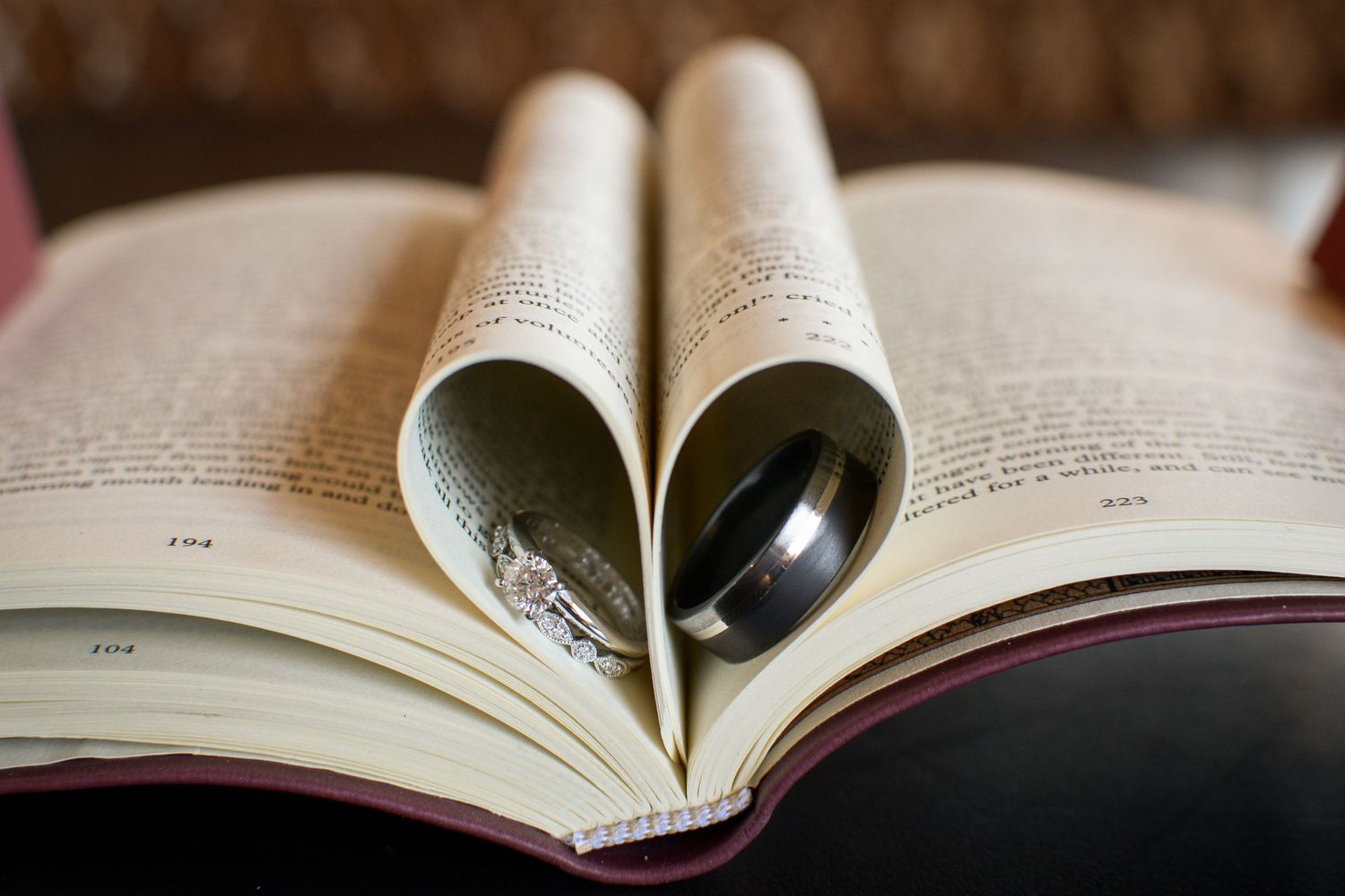 Wedding rings inside the pages of a book made into a heart shape.