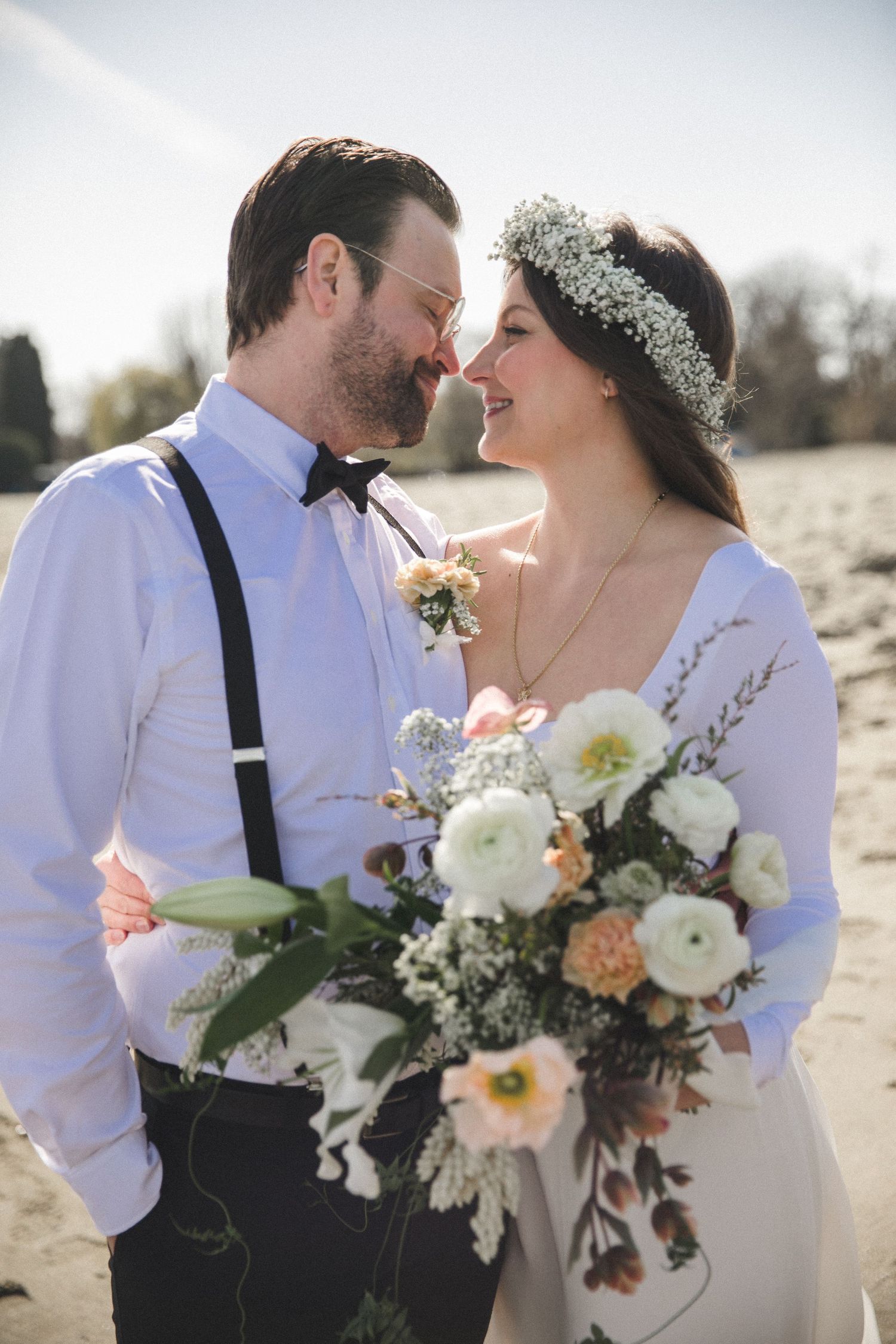 Bride and groom stare into each other's eyes while holding beautiful bouquet