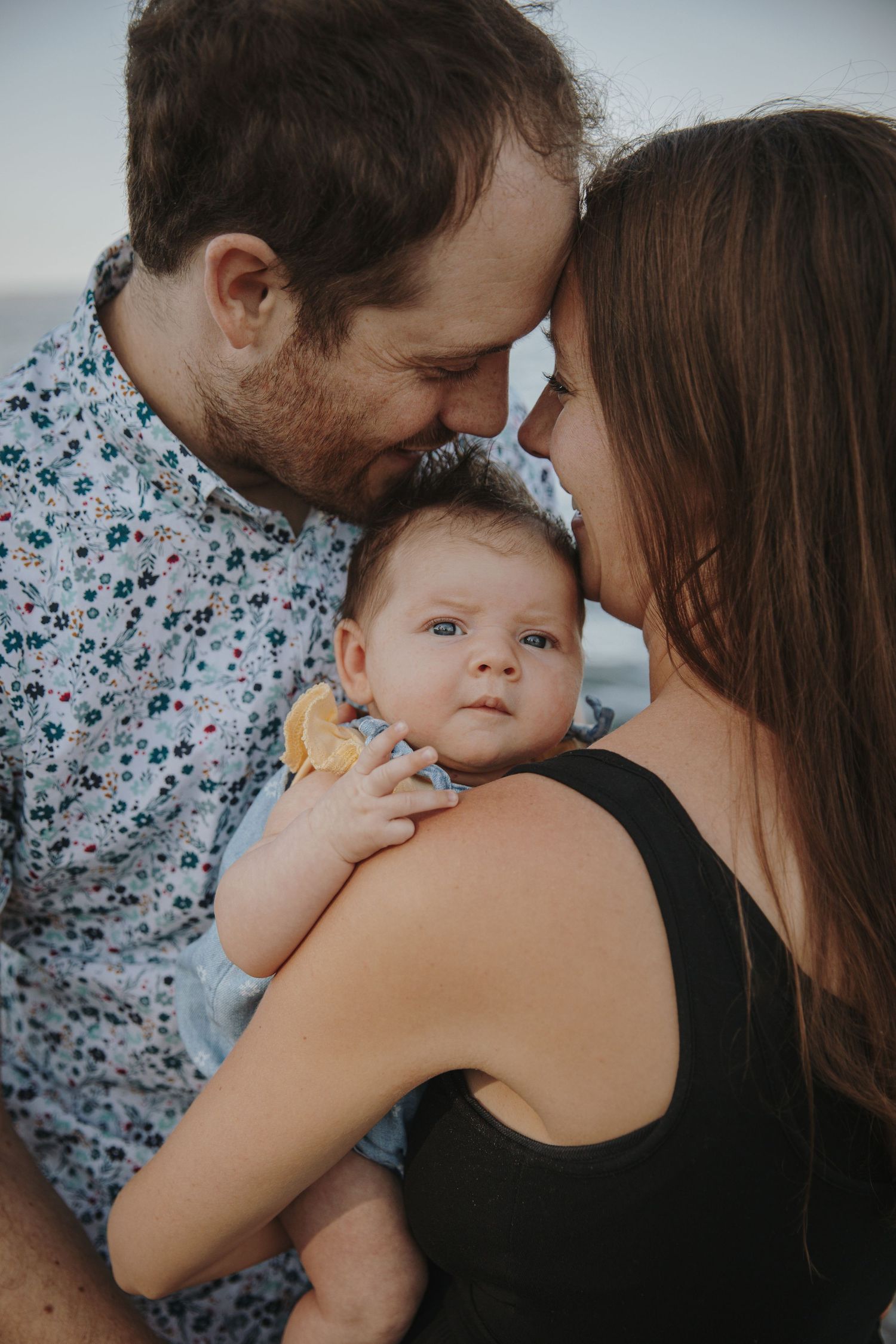 Mom and dad gaze into each other's eyes while baby looks at photographer